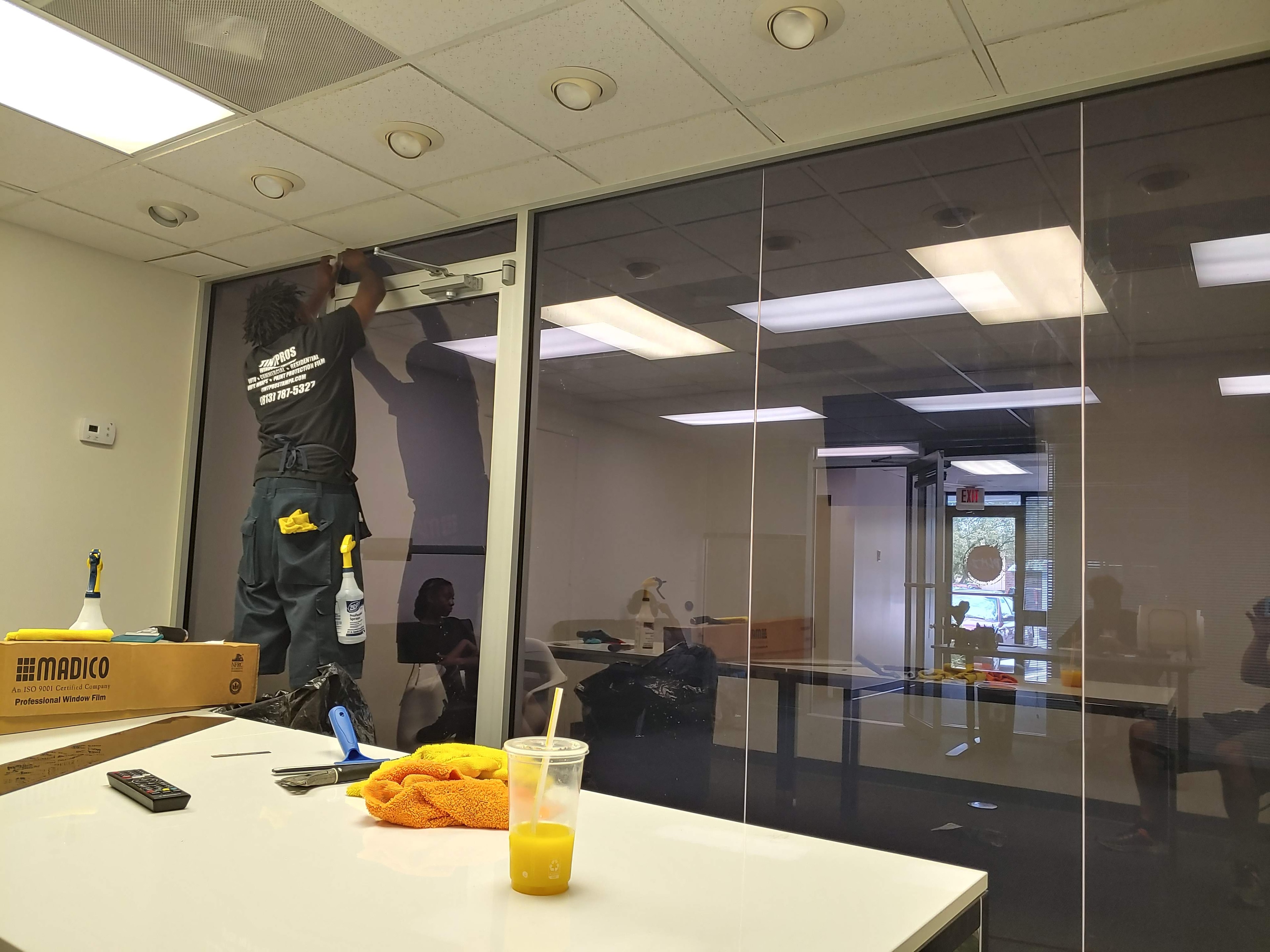 Worker installing decorative window film on glass partition